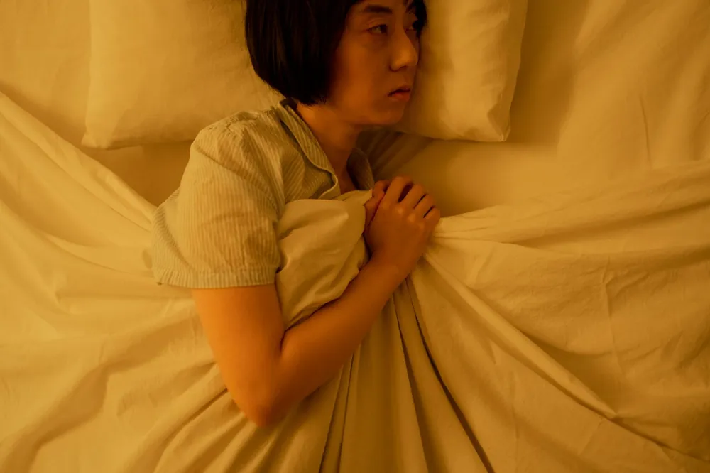 Woman restless in a warm bed, wondering if sleeping too hot causes nightmares